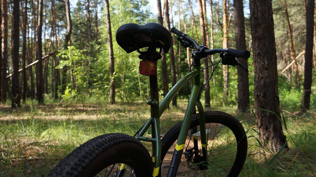 Bicikli az erdőben, túra kerékpár, zöld MTB mountain bike, erdei szabadidős közlekedés, aktiv kikapcsolódás, természet közeli bicikli, idilli erdei táj, outdoor sport, kerékpáros kaland, fajta kerékpár, bringázás a természetben, szabadban biciklizés, MTB túra, bringa az erdőben, kerékpár túrázás, outdoor szórakozás.