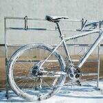 Szennyezett, jégkásás kerékpár hirdetőfelületen, színpadra állítva, külső környezetben, hideg időben, téli kerékpár, kerékpárfagyás, kerékpár és jég, kerékpár javítás, kerékpármosó, kerékpár tartozék, kerékpáripar, kerékpáros közösség, okos városi közlekedés, fenntartható mobilitás, kerékpáros életmód, kerékpár rajongók, kerékpáros kultúra, kerékpározás télen, téli kerékpár élmény, kerékpár szerelvény.