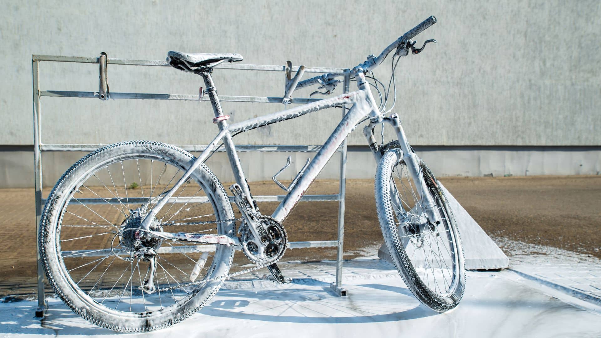 Szennyezett, jégkásás kerékpár hirdetőfelületen, színpadra állítva, külső környezetben, hideg időben, téli kerékpár, kerékpárfagyás, kerékpár és jég, kerékpár javítás, kerékpármosó, kerékpár tartozék, kerékpáripar, kerékpáros közösség, okos városi közlekedés, fenntartható mobilitás, kerékpáros életmód, kerékpár rajongók, kerékpáros kultúra, kerékpározás télen, téli kerékpár élmény, kerékpár szerelvény.